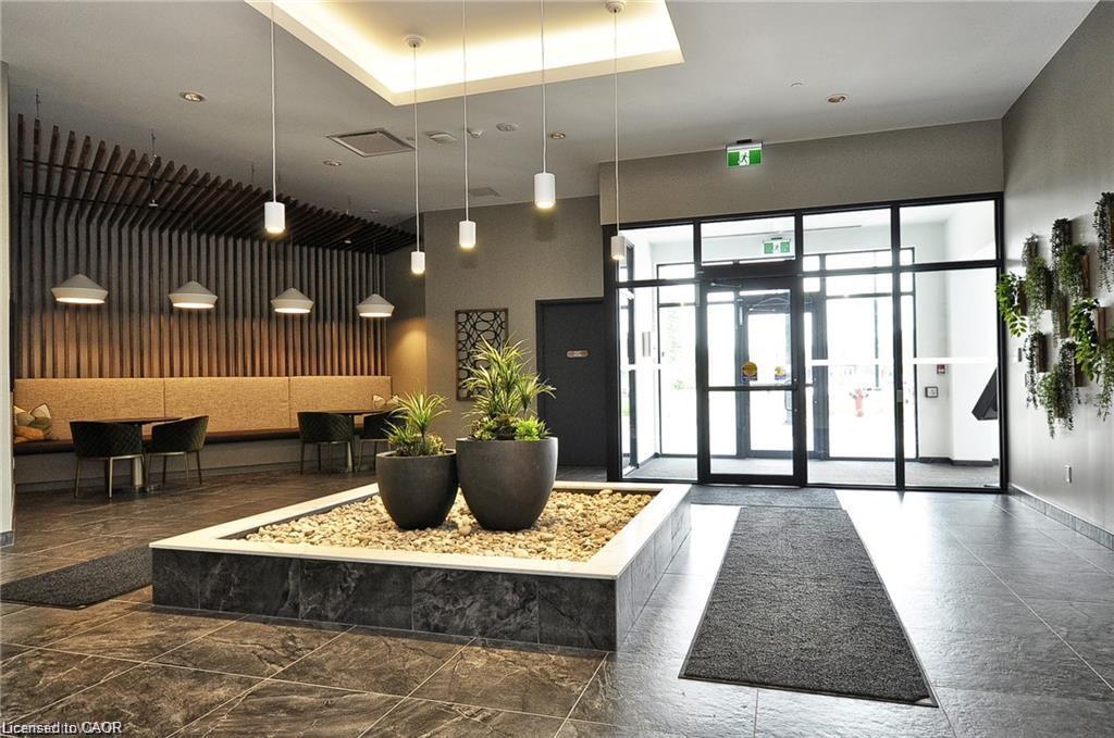Contemporary lobby with dark gray tile flooring, a central planter box with stone accents, and a lounge area featuring slatted wall detailing