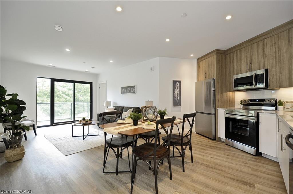 Open-concept living area with wood-finish flooring, recessed lighting, and a sliding glass door leading to a balcony