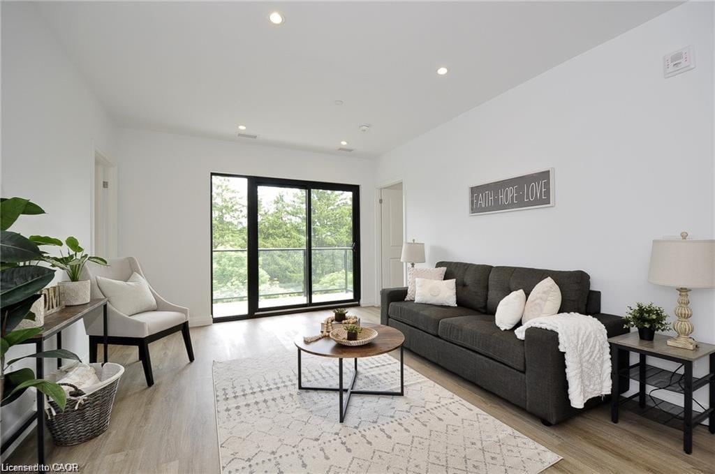 Bright living area featuring wood-finish flooring, recessed lighting, and a full-height glass sliding door with balcony access
