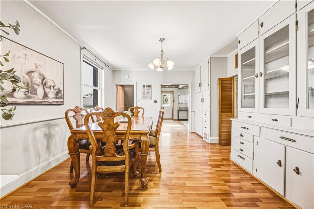 Wood-finish flooring, built-in white cabinetry with glass fronts, white baseboard trim, and a window providing natural light