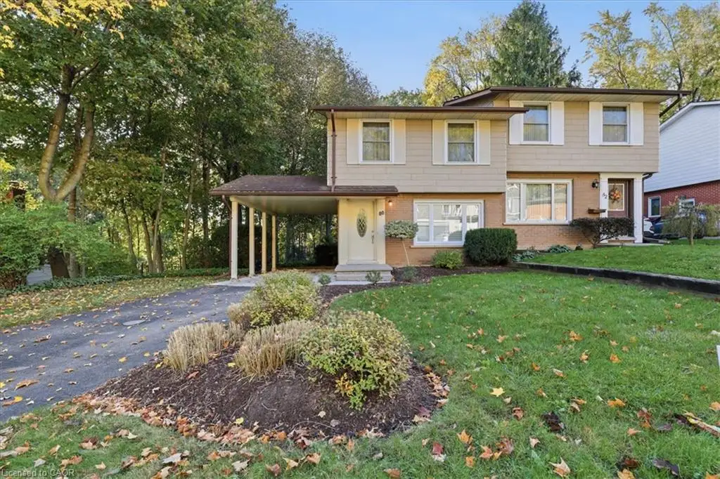 Split-level exterior featuring a combination of brick and horizontal siding, a covered carport, asphalt driveway, and mature landscaping