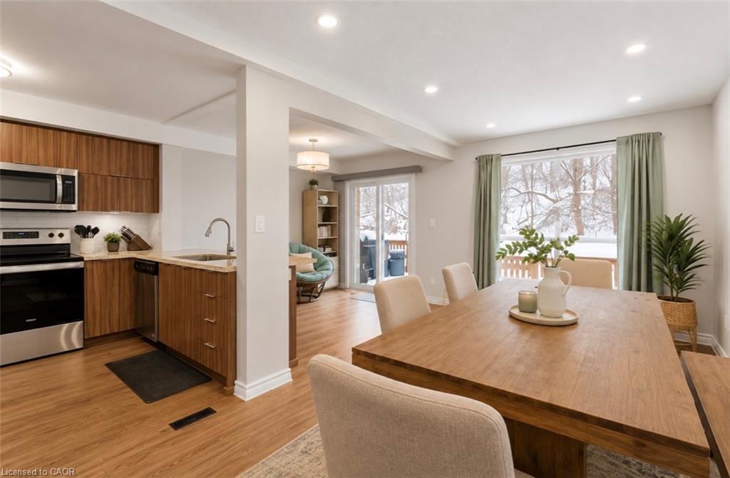 Open-concept kitchen and dining area with wood-finish flooring, recessed lighting, and a large window