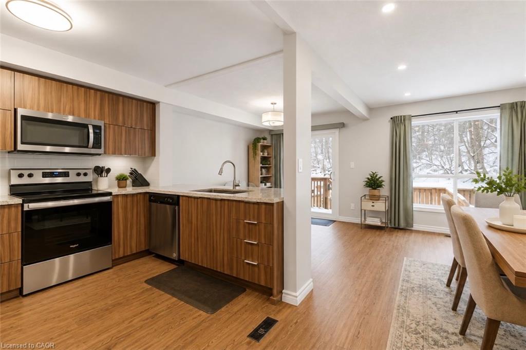 Contemporary kitchen featuring wood-finish cabinetry, stainless steel appliances, granite-style countertops, and a white subway tile backsplash