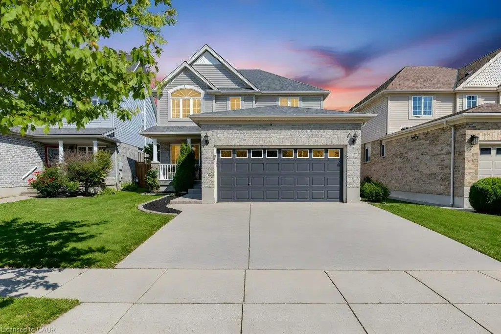 Two-story residence featuring a prominent garage, a light-colored brick exterior, and a well-maintained lawn