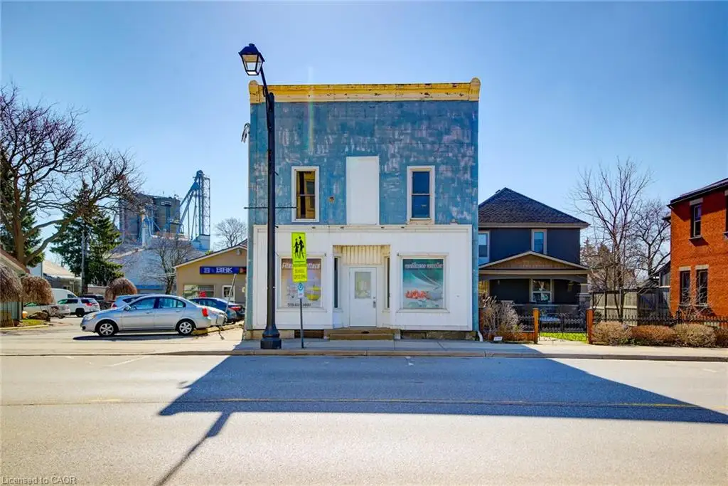 This property features a two-story facade with a blue upper level and a white lower level, including a central entrance door and two display windows