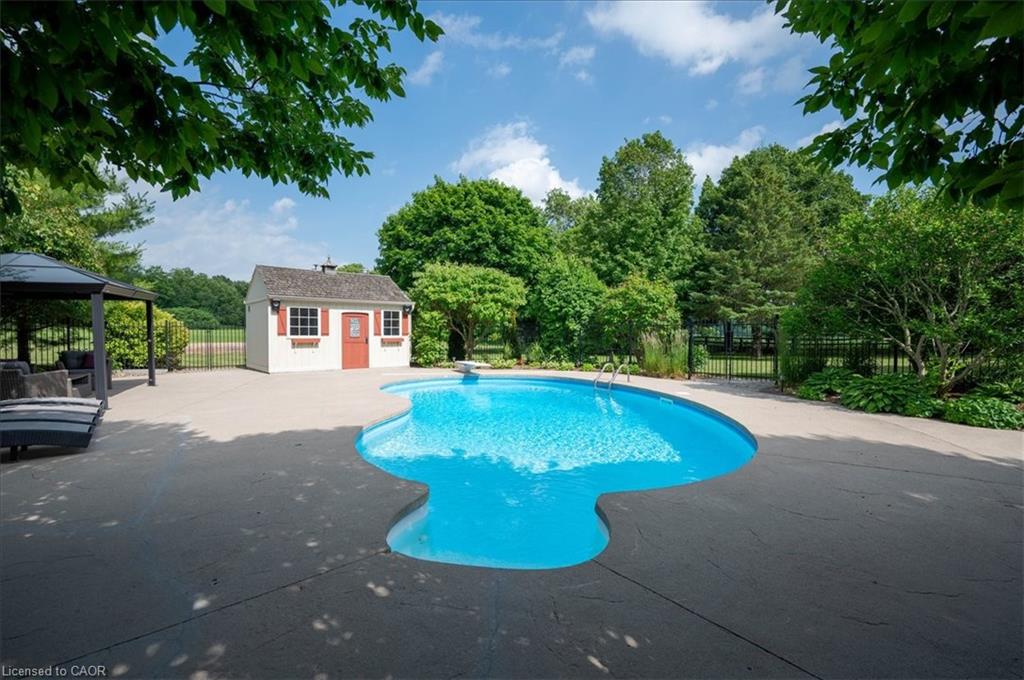 Freeform swimming pool with expansive stamped concrete decking and large sitting or entertaining area and pool house with gas pool heater.