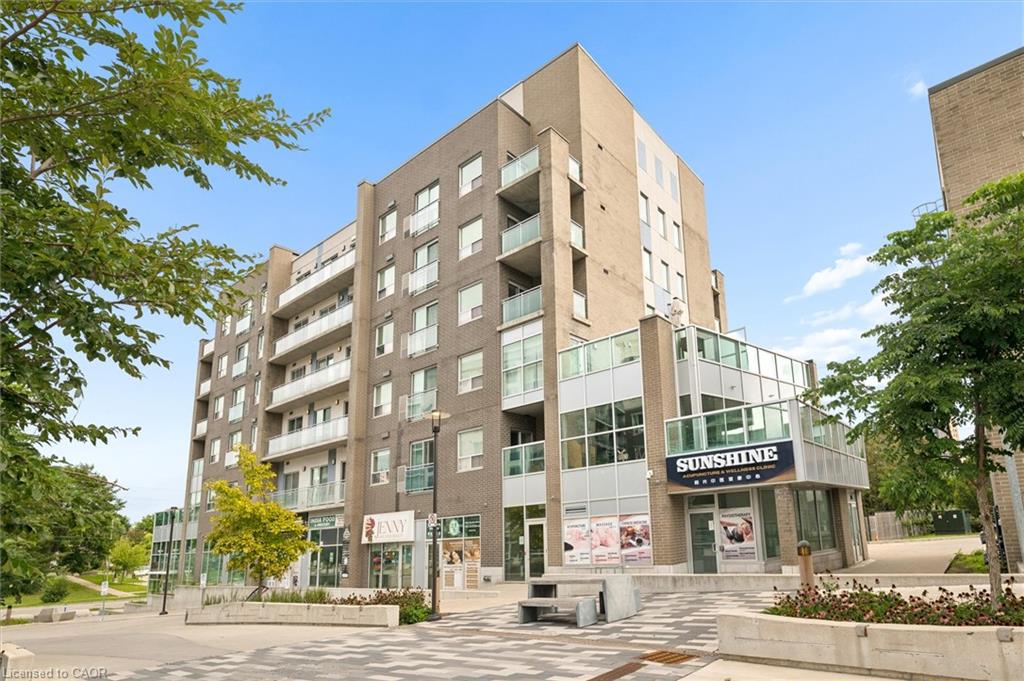 Multi-story building featuring a brick exterior, multiple private balconies with glass railings, ground-level retail spaces, and integrated landscaping with mature trees