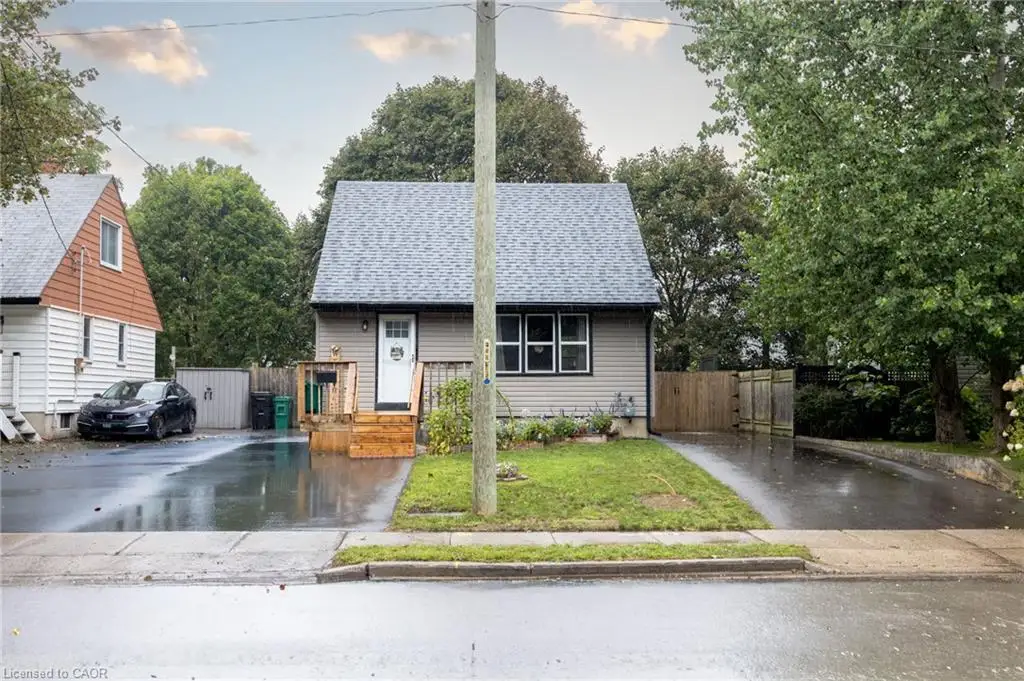 Gray shingle roof, light gray siding, white front door, wooden front steps, and a paved driveway