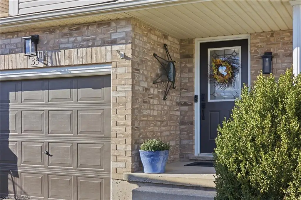 Brick facade, panel-style garage door, leaded-glass front door, exterior sconce lighting, concrete porch