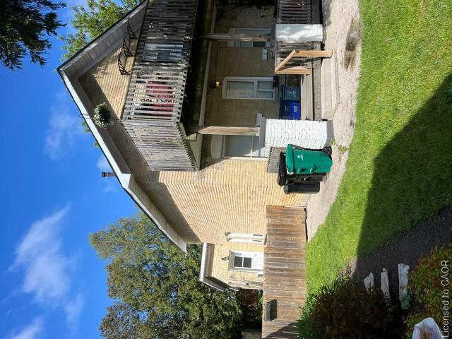 Brick exterior with a second-story wooden balcony, a ground-level covered porch, and a fenced yard featuring a grassy area