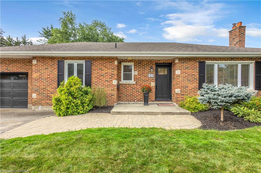 Brick exterior with a dark front door, a paved walkway, a concrete porch, and a single-car garage
