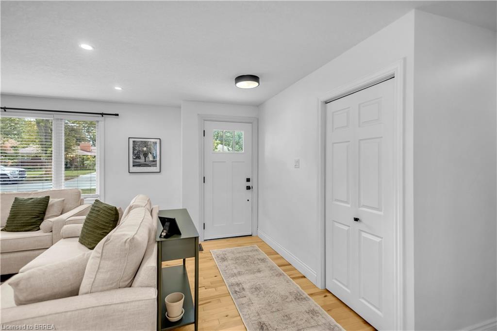 Light wood-finish flooring, recessed lighting, and a white six-panel interior door