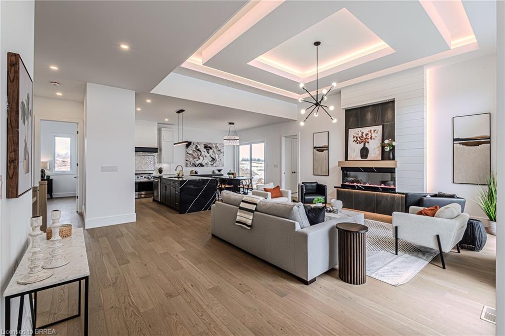 Open-concept living space featuring wood-finish flooring, a contemporary fireplace, and a coffered ceiling with integrated lighting