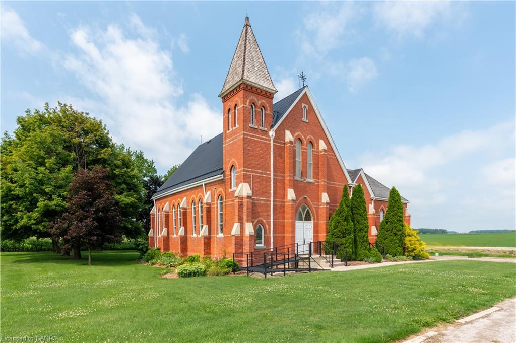 Red brick exterior with arched windows, a prominent steeple, and a dark shingle roof