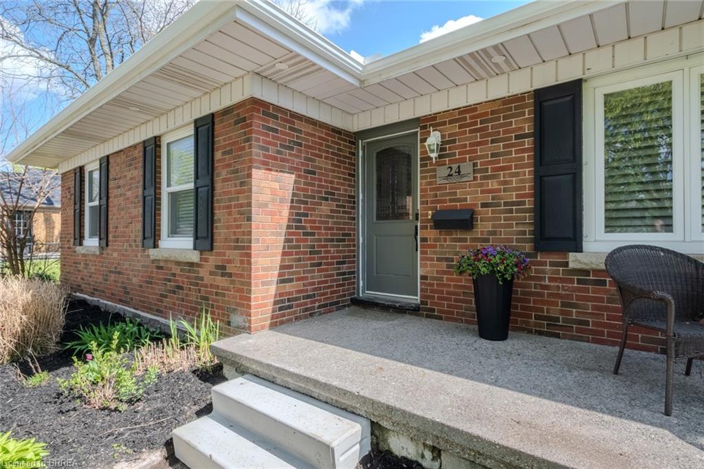 Brick exterior featuring white window frames with dark shutters, a covered entry, and concrete steps