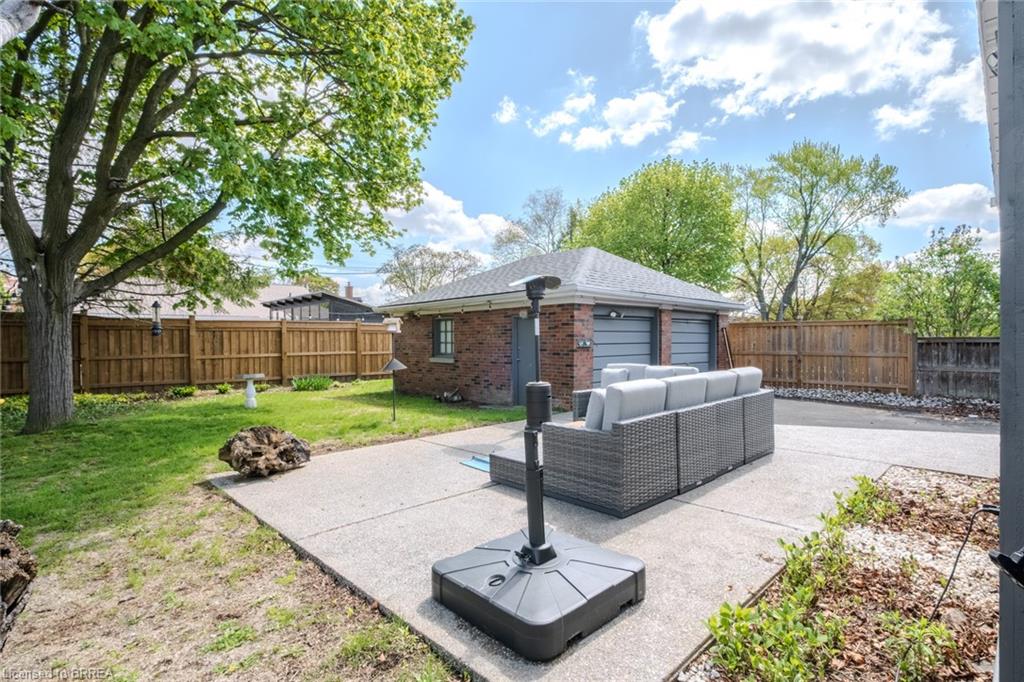 Spacious backyard featuring a large concrete patio, expansive lawn, and mature trees