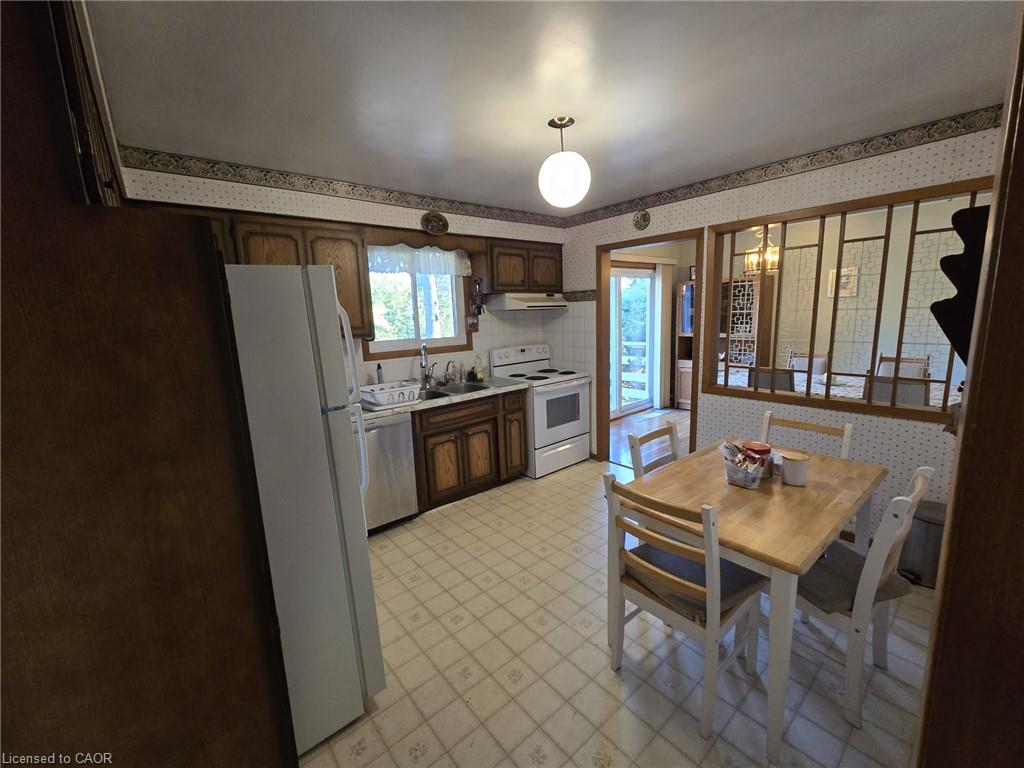 Kitchen featuring wood-finish cabinetry, white appliances, and a tiled floor