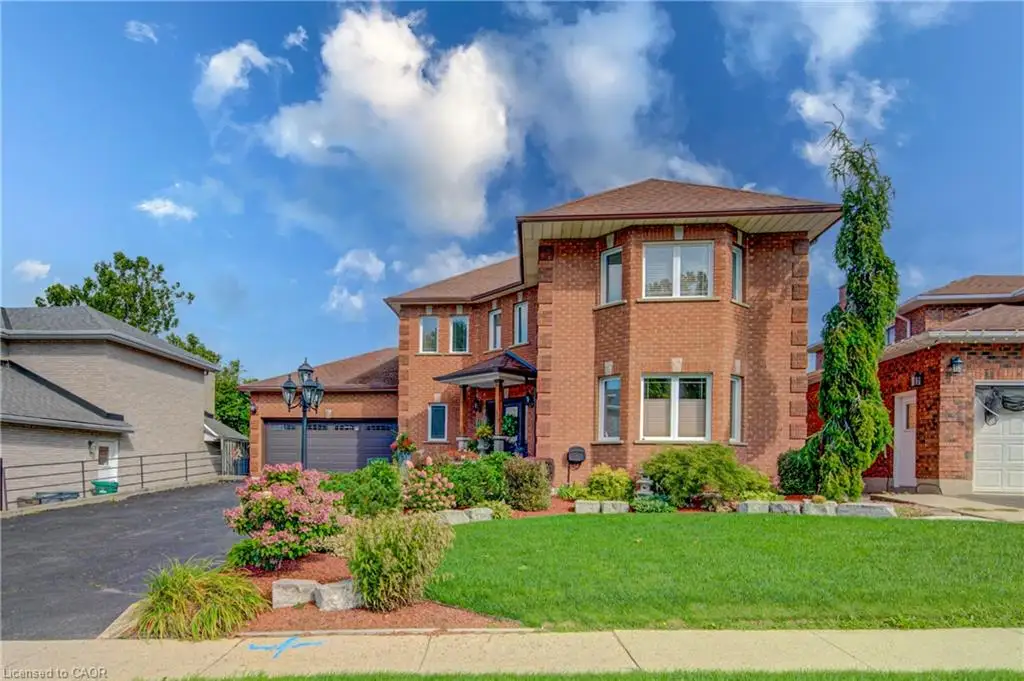 Brick exterior, dual-car garage, mature landscaping, paved driveway, and established front lawn