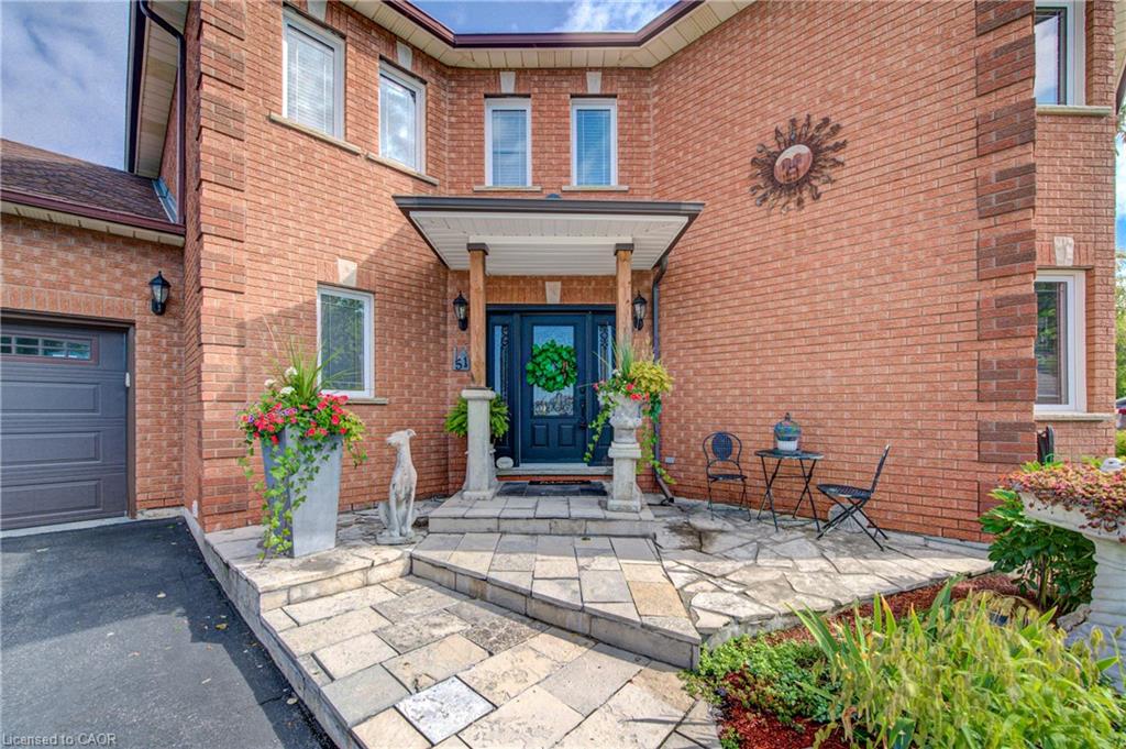 Brick exterior with a covered porch entry, stone pathway, and an attached garage