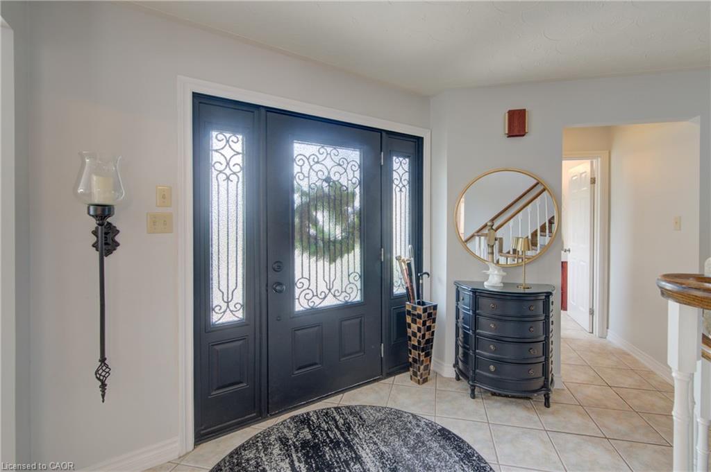 Entryway featuring a double door with decorative glass inserts, a wall-mounted sconce, and tile flooring