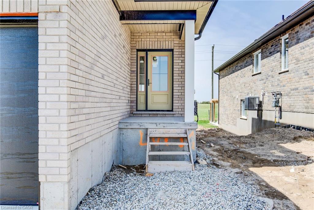 Main entrance featuring a covered porch with a white column, a light-colored entry door with windowpanes, and a concrete landing